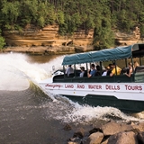 A duck boat splashes into the water.