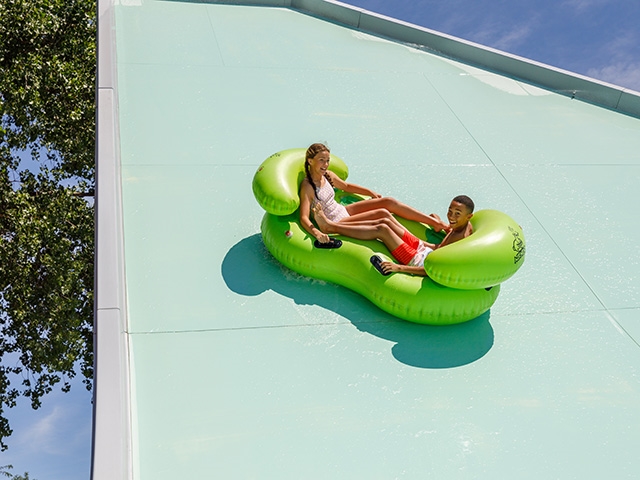 Two people in bright green tube sliding on waterslide
