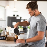 A person adding cream to their coffee.