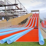 Side view of blue end red tubing hill with ropes course in the background.