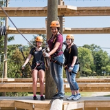 People cross a log on the ropes course at BigFoot Ropes Course.