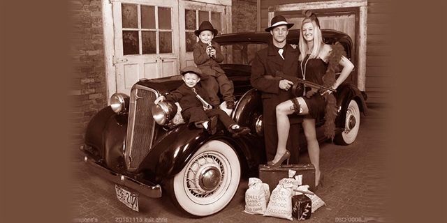 Family posing in front of a vintage car.