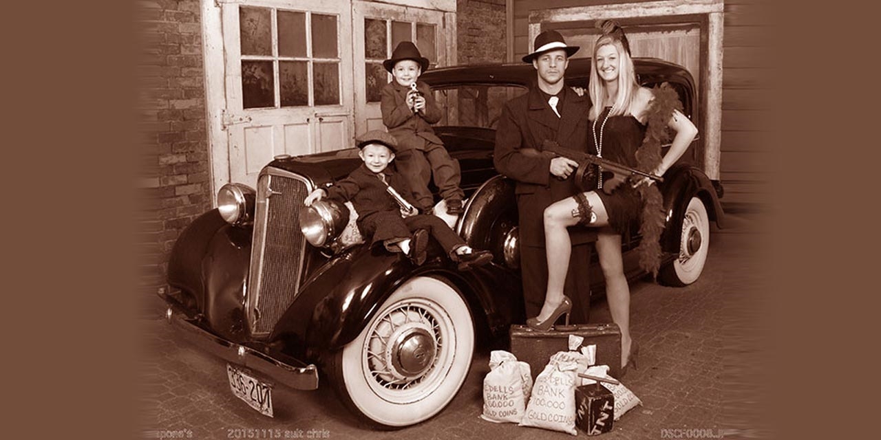 Family posing in front of a vintage car.