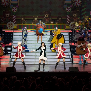 Dancers and singers on a holiday stage setting.