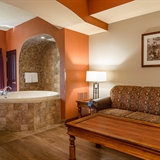 Bathtub with nearby high-top table and seats and sofa.