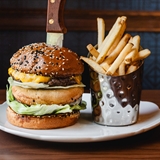 Tall burger served with fries.