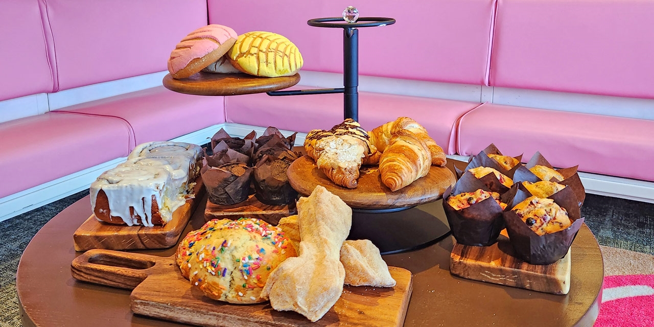 Selection of pastries on a table in front of pink interior.