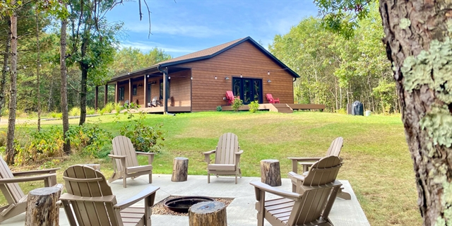 A house exterior and firepit with chairs.