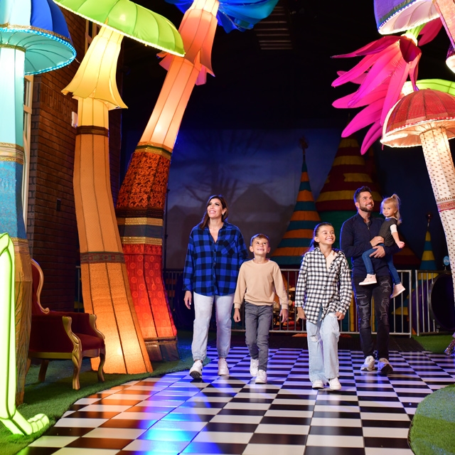 Family walking through colorful mushroom setting.