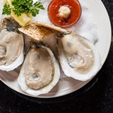 Oysters with lemon, garnish, dipping sauce, and a cocktail.