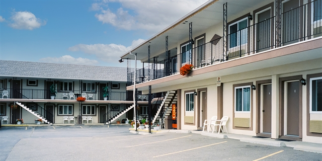 Finch Motel exterior with hanging plants and chairs.