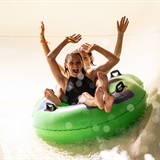 Two people on an inner tube slide down a waterslide.