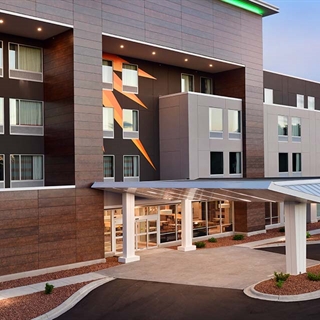 A grey hotel building stands in front of scenic woods in Wisconsin Dells