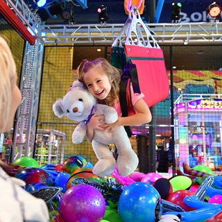 Little girl riding on a human claw machine.
