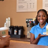 Barista handing out Starbucks coffee.