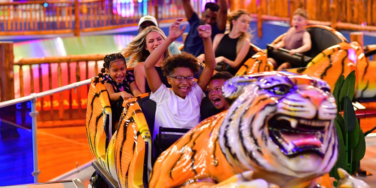 Families riding tiger train looking kids' rollercoaster.