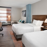 Two bed bedroom with televisions, desk, office chair, and lamp.