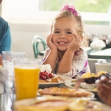 A child enjoying breakfast with their family.