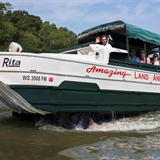 A duck boat emerges from the water.