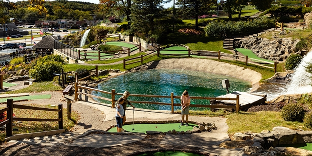 A family plays mini-golf.