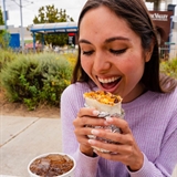 Girl biting into a burrito.