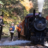 Family next to a small steam train.