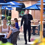 Servers bring food and drinks to people dining outside.