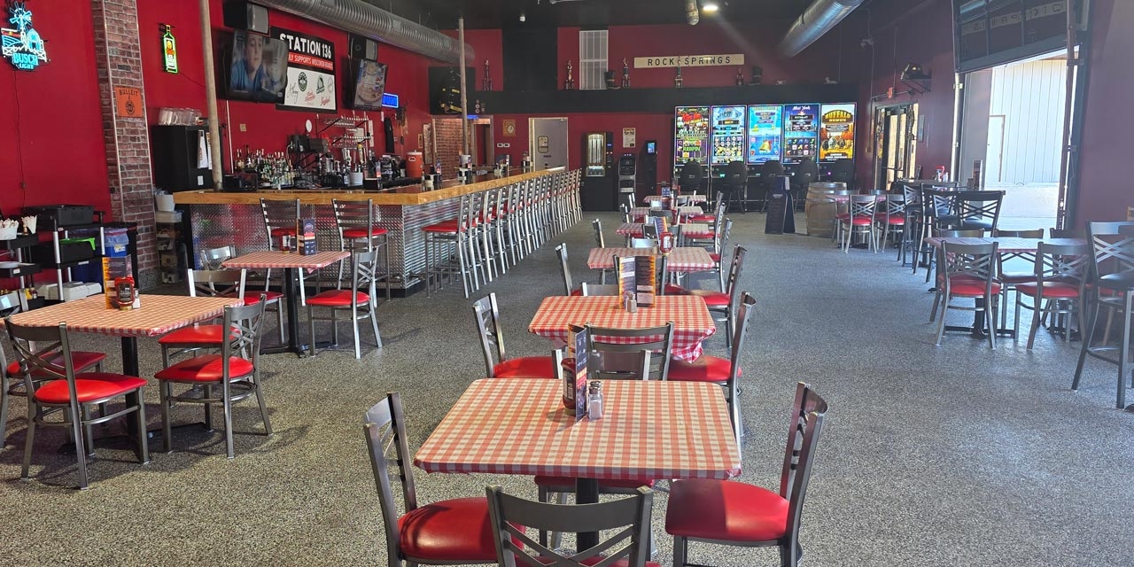 Interior of a small restaurant with garage doors and a bar.