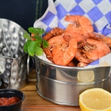 A shrimp basket with dipping sauce and a lemon.