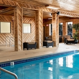 Indoor pool and hot tub with poolside chairs.
