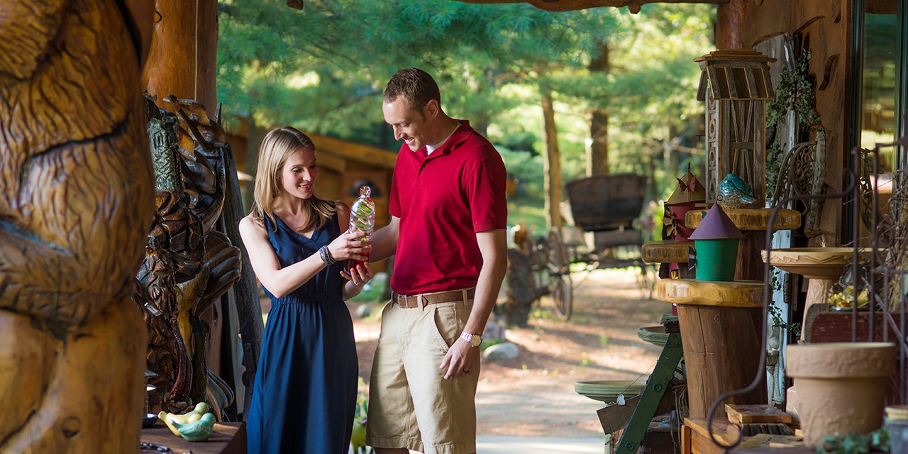 A couple looks at glass, wood, and metal decorations.