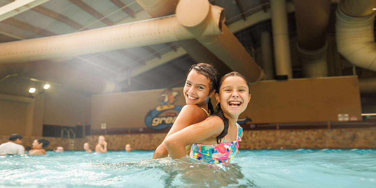 Two siblings having fun in a wave pool.