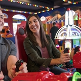 A couple plays a space arcade game.