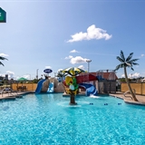 Outdoor pool area with waterslides and poolside seats.